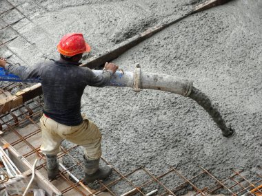 Kuala Lumpur, Malezya - 27 Nisan 2017: İnşaat işçilerinden oluşan bir grup, beton pompadaki beton hortumu kullanarak inşaat alanındaki kereste biçimine döküyorlar..  