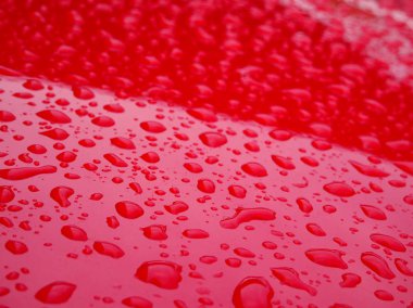 Kırmızı metalin tepesindeki yağmur damlasına odaklanmış. 