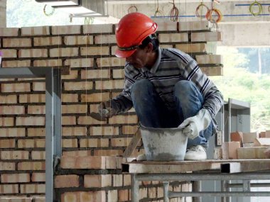 Kuala Lumpur, Malezya-29 Mart 2017: bricklayer kil tuğla yatıyordu ve inşaat yerinde duvarlar oluşturmak için çimento harç kullanarak birlikte yığılmış. Bu iş için gerekli araçlar gereklidir. 