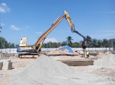 SELANGOR, MALAYSIA 15 Mart 2016: İnşaat alanında çarşaf yığını cofferdam sürücü makine. Makine titreşimli hidrolik kol kullanarak çarşaf yığınını yere itti. İşçi kontrolü. 