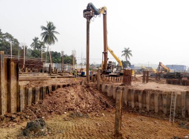 SELANGOR, MALAYSIA 15 Mart 2016: İnşaat alanında çarşaf yığını cofferdam sürücü makine. Makine titreşimli hidrolik kol kullanarak çarşaf yığınını yere itti. İşçi kontrolü. 