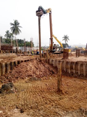 SELANGOR, MALAYSIA 15 Mart 2016: İnşaat alanında çarşaf yığını cofferdam sürücü makine. Makine titreşimli hidrolik kol kullanarak çarşaf yığınını yere itti. İşçi kontrolü. 