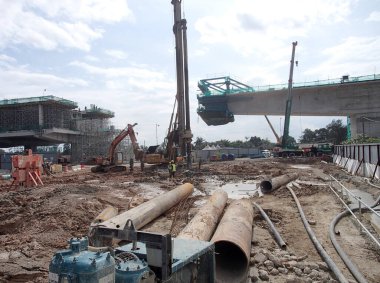 SELANGOR, MALAYSIA 15 Mart 2016: İnşaat alanında çarşaf yığını cofferdam sürücü makine. Makine titreşimli hidrolik kolu kullanarak çarşaf yığınını yere itti. İşçi kontrolü. 