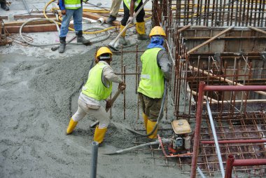 SELANGOR, MALAYSIA -18 Haziran 2016: İnşaat alanında beton vibratör kullanan inşaat işçileri, resmi çalışmanın üzerine dökülen beton çamuru sıkıştırmak için. 