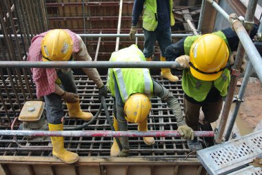 SELANGOR, MALAYSIA -18 Haziran 2016: İnşaat alanında beton vibratör kullanan inşaat işçileri, resmi çalışmanın üzerine dökülen beton çamuru sıkıştırmak için. 