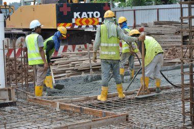 SELANGOR, MALAYSIA -18 Haziran 2016: İnşaat alanında beton vibratör kullanan inşaat işçileri, resmi çalışmanın üzerine dökülen beton çamuru sıkıştırmak için. 