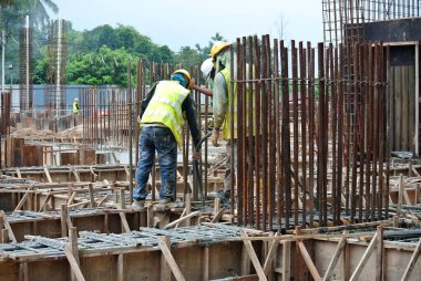 SELANGOR, MALAYSIA -18 Haziran 2016: İnşaat alanında beton vibratör kullanan inşaat işçileri, resmi çalışmanın üzerine dökülen beton çamuru sıkıştırmak için. 