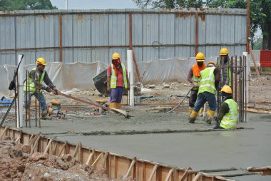 SELANGOR, MALAYSIA -18 Haziran 2016: İnşaat alanında beton vibratör kullanan inşaat işçileri, resmi çalışmanın üzerine dökülen beton çamuru sıkıştırmak için. 