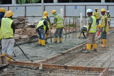 SELANGOR, MALAYSIA -18 Haziran 2016: İnşaat alanında beton vibratör kullanan inşaat işçileri, resmi çalışmanın üzerine dökülen beton çamuru sıkıştırmak için. 