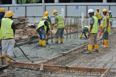 SELANGOR, MALAYSIA -JUNE 18, 2016: Construction workers using a concrete vibrator at the construction site to compact the concrete slurry that pours in the formwork.  clipart