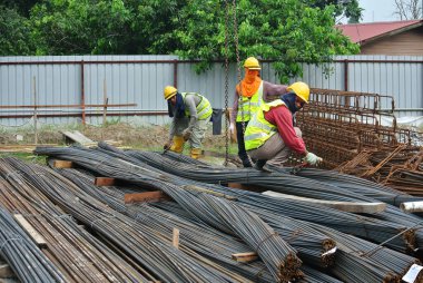 SERDANG, MALAYSIA - 26 Kasım 2016: İnşaat işçileri vinç kullanarak bir demet çelik takviyesi taşıyorlar.