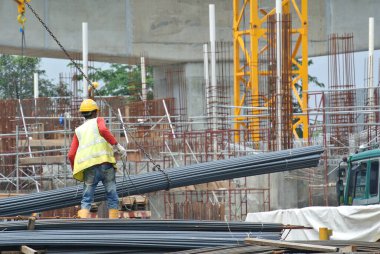 SERDANG, MALAYSIA - 26 Kasım 2016: İnşaat işçileri vinç kullanarak bir demet çelik takviyesi taşıyorlar.