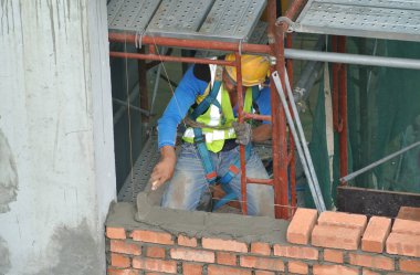 JOHOR, MALAYSIA -AĞUSTOS 05, 2016: İnşaat alanında inşaat duvarları oluşturmak için tuğla döşeyen tuğla ustası. 