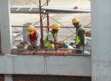 JOHOR, MALAYSIA -AĞUSTOS 05, 2016: İnşaat alanında inşaat duvarları oluşturmak için tuğla döşeyen tuğla ustası. 