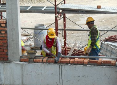 JOHOR, MALAYSIA -AĞUSTOS 05, 2016: İnşaat alanında inşaat duvarları oluşturmak için tuğla döşeyen tuğla ustası. 