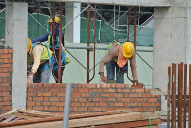 JOHOR, MALAYSIA -AĞUSTOS 05, 2016: İnşaat alanında inşaat duvarları oluşturmak için tuğla döşeyen tuğla ustası. 