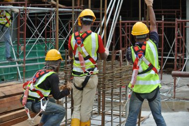 MALACCA, MALAYSIA -27 Haziran 2016: Malezya 'nın Malacca kentindeki inşaat alanında çelik takviye barı üreten inşaat işçileri. Destek çubuğu ince bir kabloyla birbirine bağlanmış..  