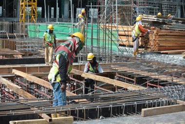 MALACCA, MALAYSIA -27 Haziran 2016: Malezya 'nın Malacca kentindeki inşaat alanında çelik takviye barı üreten inşaat işçileri. Destek çubuğu ince bir kabloyla birbirine bağlanmış..  