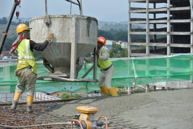 KUALA LUMPUR, MALAYSIA - 8 AĞUSTOS 2018: İnşaat alanında taşınabilir vinç kovasını kullanarak ıslak beton döken bir grup inşaat işçisi.  