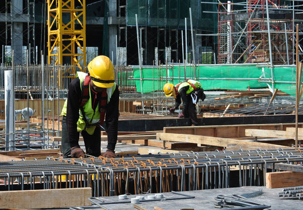 MALACCA, MALAYSIA -JUNE 27, 2016: Construction workers fabricating steel reinforcement bar at the construction site in Malacca, Malaysia. The reinforcement bar was tied together using tiny wire.  