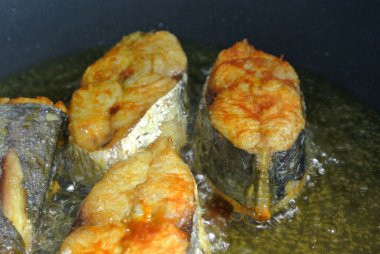 İspanyol uskumruları, kalın dilimlere ayrılıp, kızgın yağ ile kızartılıyor. Balık dilimlerine önceden zerdeçal tozu serpilmişti..