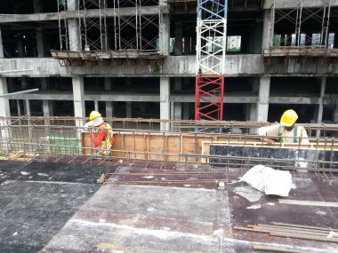 SEREMBAN, MALAYSIA - 29 Mart 2020: İnşaat işçileri inşaat alanında çelik takviye çubuğu üretiyorlar. Küçük kabloları kullanarak birbirlerine bağladılar. Bu, takviye beton yapımında atılan adımlardan biridir.. 