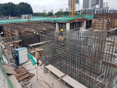 SEREMBAN, MALAYSIA - 29 Mart 2020: İnşaat işçileri inşaat alanında çelik takviye çubuğu üretiyorlar. Küçük kabloları kullanarak birbirlerine bağladılar. Bu, takviye beton yapımında atılan adımlardan biridir.. 
