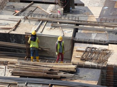 SEREMBAN, MALAYSIA - 29 Mart 2020: İnşaat işçileri inşaat alanında çelik takviye çubuğu üretiyorlar. Küçük kabloları kullanarak birbirlerine bağladılar. Bu, takviye beton yapımında atılan adımlardan biridir.. 