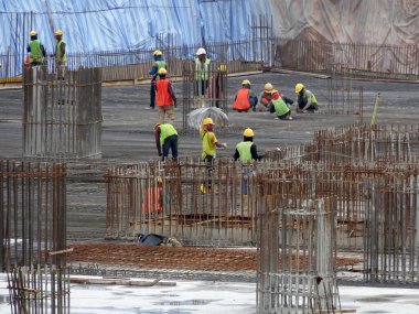 SEREMBAN, MALAYSIA - 29 Mart 2020: İnşaat işçileri inşaat alanında çelik takviye çubuğu üretiyorlar. Küçük kabloları kullanarak birbirlerine bağladılar. Bu, takviye beton yapımında atılan adımlardan biridir.. 