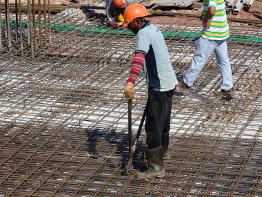 SEREMBAN, MALAYSIA - 29 Mart 2020: İnşaat işçileri inşaat alanında çelik takviye çubuğu üretiyorlar. Küçük kabloları kullanarak birbirlerine bağladılar. Bu, takviye beton yapımında atılan adımlardan biridir.. 
