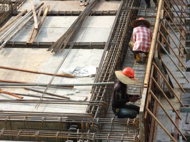 SEREMBAN, MALAYSIA - 29 Mart 2020: İnşaat işçileri inşaat alanında çelik takviye çubuğu üretiyorlar. Küçük kabloları kullanarak birbirlerine bağladılar. Bu, takviye beton yapımında atılan adımlardan biridir.. 