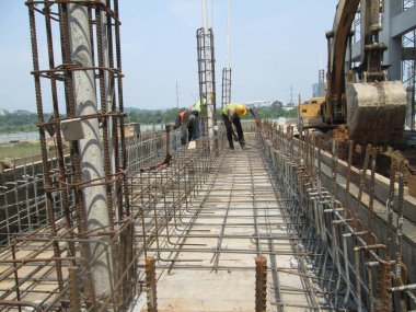 SEREMBAN, MALAYSIA - 29 Mart 2020: İnşaat işçileri inşaat alanında çelik takviye çubuğu üretiyorlar. Küçük kabloları kullanarak birbirlerine bağladılar. Bu, takviye beton yapımında atılan adımlardan biridir.. 