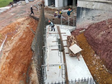 SEREMBAN, MALAYSIA - 29 Mart 2020: İnşaat işçileri inşaat alanında çelik takviye çubuğu üretiyorlar. Küçük kabloları kullanarak birbirlerine bağladılar. Bu, takviye beton yapımında atılan adımlardan biridir.. 