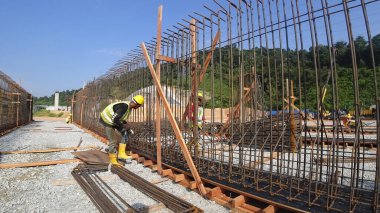 SEREMBAN, MALAYSIA - 29 Mart 2020: İnşaat işçileri inşaat alanında çelik takviye çubuğu üretiyorlar. Formatörleri kullanmadan önce küçük kabloları kullanarak birbirlerine bağladılar.. 