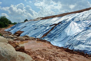 SEREMBAN, MALASIA - 3 Mart 2019: Plastik tabaka erozyonu önlemek için yamacın yüzeyine yayıldı. Ayrıca geçici olarak dengeleme işlemi bitmeden önce eğimi sabitlemek için..