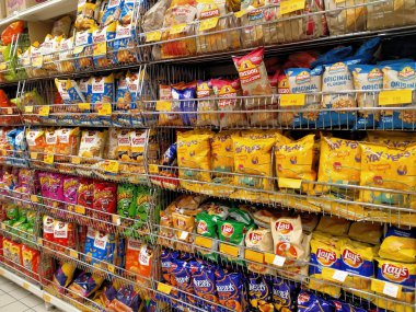 KUALA LUMPUR, MALAYSIA -APRIL 27, 2020: Markette raflarda ve satılık abur cuburlar ve paketlenmiş çeşitli abur cuburların seçici odak noktası. Her birinin kendi fiyat etiketi var.. 