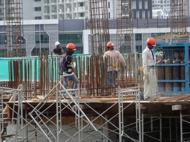 KUALA LUMPUR, MALAYSIA - 23 AĞUSTOS 2019: Gündüzleri Malezya 'daki şantiyede çalışan inşaat işçileri. Bir kazadan kaçınmak için uygun güvenlik teçhizatı giymeleri gerekiyor.. 