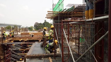 KUALA LUMPUR, MALAYSIA - 23 AĞUSTOS 2019: Gündüzleri Malezya 'daki şantiyede çalışan inşaat işçileri. Bir kazadan kaçınmak için uygun güvenlik teçhizatı giymeleri gerekiyor.. 