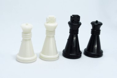 Siyah ve beyaz satranç taşlarına odaklanmış, hepsi beyaz bir arkaplanda rastgele sıralanmış.. 