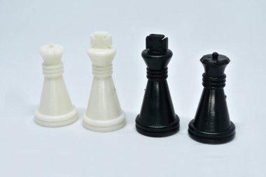 Siyah ve beyaz satranç taşlarına odaklanmış, hepsi beyaz bir arkaplanda rastgele sıralanmış.. 