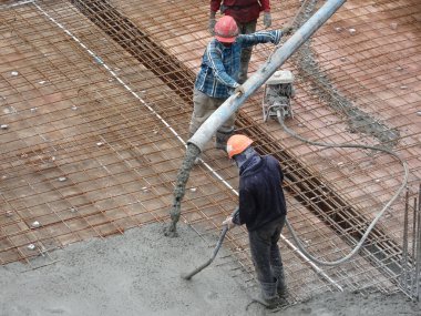 KUALA LUMPUR, MALAYSIA - 16 Haziran 2017: İnşaat işçileri inşaat sahasındaki beton pompalama makinesinin beton örümcek hortumunu kullanarak beton beton döşeyen inşaat işçileri.  