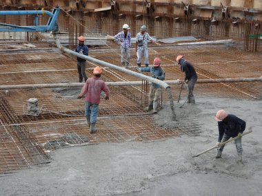 KUALA LUMPUR, MALAYSIA - 16 Haziran 2017: İnşaat işçileri inşaat sahasındaki beton pompalama makinesinin beton örümcek hortumunu kullanarak beton beton döşeyen inşaat işçileri.  