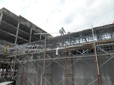 KUALA LUMPUR, MALAYSIA -APRIL 24, 2017: İnşaat işçileri inşaat sahasına metal çatı kirişleri yapı kuruyorlar. Yükseklikte çalışma. 