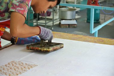 KUALA LUMPUR, MALAYSIA - 25 HAZİRAN 2016: El yapımı damga batik. Sanatçı tuşu batik tekap ya da pul batik kalıbını kullanarak batik deseni alır. 