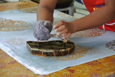 KUALA LUMPUR, MALAYSIA - 25 HAZİRAN 2016: El yapımı damga batik. Sanatçı tuşu batik tekap ya da pul batik kalıbını kullanarak batik deseni alır. 