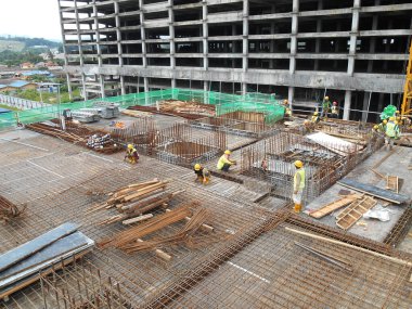 SEREMBAN, MALAYSIA - 29 Mart 2020: İnşaat işçileri inşaat alanında çelik takviye çubuğu üretiyorlar. Formatörleri kullanmadan önce küçük kabloları kullanarak birbirlerine bağladılar.. 