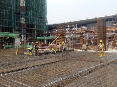 SEREMBAN, MALAYSIA - 29 Mart 2020: İnşaat işçileri inşaat alanında çelik takviye çubuğu üretiyorlar. Formatörleri kullanmadan önce küçük kabloları kullanarak birbirlerine bağladılar.. 