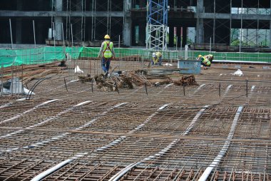 SEREMBAN, MALAYSIA - 29 Mart 2020: İnşaat işçileri inşaat alanında çelik takviye çubuğu üretiyorlar. Formatörleri kullanmadan önce küçük kabloları kullanarak birbirlerine bağladılar.. 