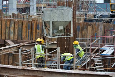 KUALA LUMPUR, MALAYSIA - 8 AĞUSTOS 2018: İnşaat alanında taşınabilir vinç kovasını kullanarak ıslak beton döken bir grup inşaat işçisi.  