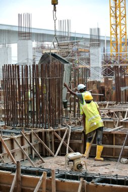 KUALA LUMPUR, MALAYSIA - 8 AĞUSTOS 2018: İnşaat alanında taşınabilir vinç kovasını kullanarak ıslak beton döken bir grup inşaat işçisi.  